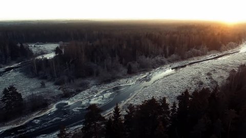 AERIAL: Winter forest flight at sunset. Snowy Siberian wood. flying along a winding river