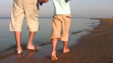 walking father with son on beach 