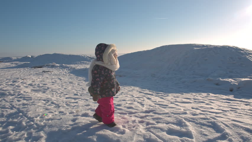 Young mother playing with her baby in sunny winter day on the frozen lake