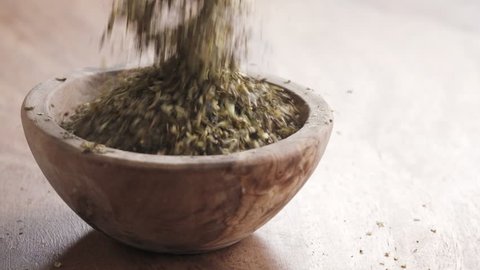 Slow motion of provence herbs falling in wood bowl on wooden table, 180fps prores footage