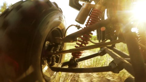 4K with sound : Shock-absorbers and a wheel of an ATV going through terrain