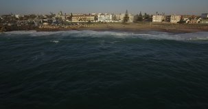 Drone video with view of Namibian Atlantic coastline, Swakopmund vintage buildings and beach, surf break point and landscape with ocean background of Swakopmund holiday resort at Namibia's west coast