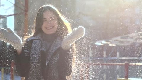 Beautiful Young Smiling Winter Girl Blowing Snow . Slow Motion. Woman blows snow with hands on nature.  city background. Beautiful Girl Winter Vintage Blowing Snow at Camera