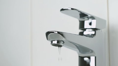 Chrome-plated tap in bathtub. Weak flow of water pouring from chrome-plated tap. Close-up