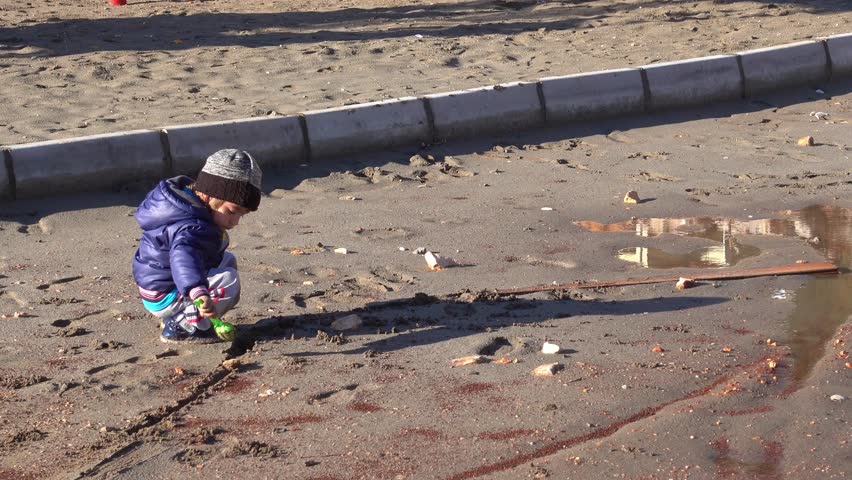 4K Zoom out boy playing in puddle against children playground
