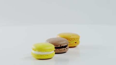 Three colourful macarons are rotating together on the white surface