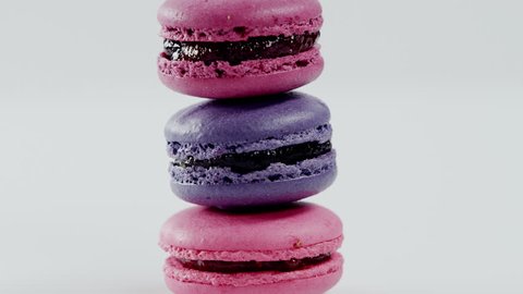 Three colourful macarons, which lay on each other, are rotating before the camera