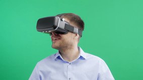 Man in a virtual reality mask observing digital video game world. Green screen. VR. 4K.