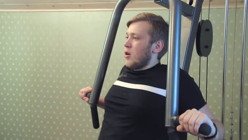 Young man works out on his home gym equipment to exercise his chest muscles
