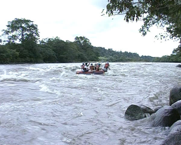 People in rubber boat sail down wildwater river. Extreme risky tourist recreation.