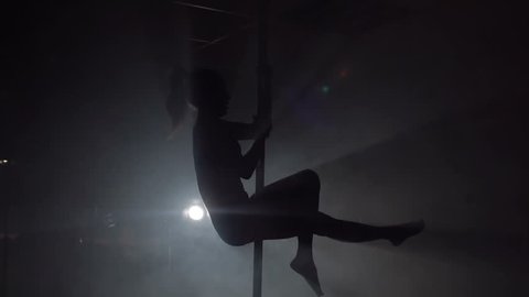 Young woman exercising pole dance fitness, slow motion. Silhouette.