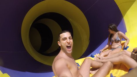 Friends having fun and sliding down in a colorful water slide