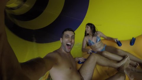 Friends having fun and sliding down in a colorful water slide