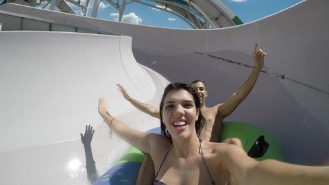 Couple having fun and sliding down in a water slide