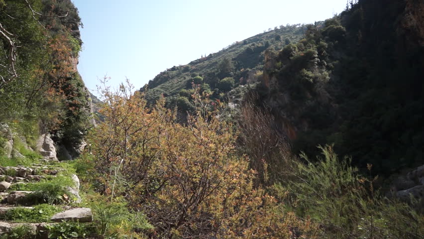 KOURA, LEBANON - CIRCA 2013: Pan-right to a man descending on the footpath leading to the medieval Greek Orthodox monastery of Our Lady of Hammatoura 