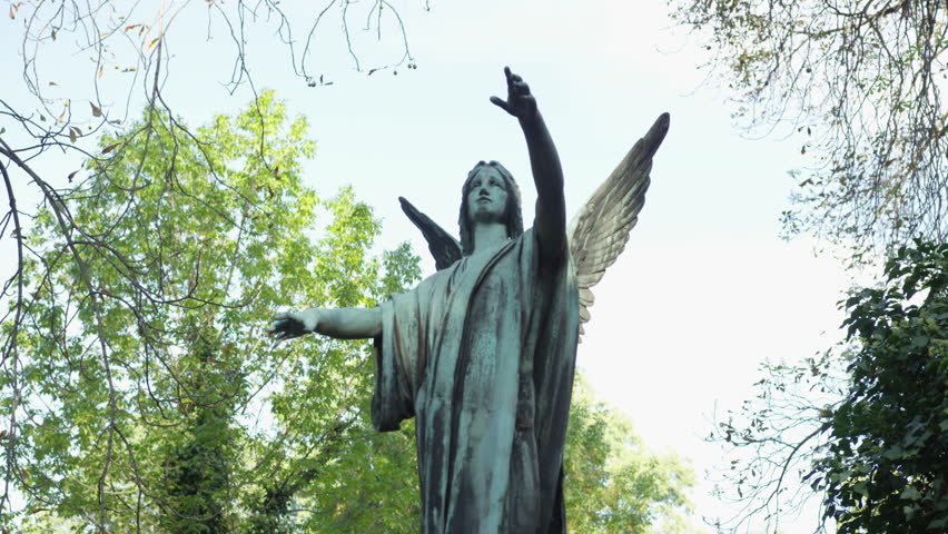 A moving shot that rotates around the statue of an angel reaching to the heavens in a cemetery. 4k.
 Royalty-Free Stock Footage #23974333