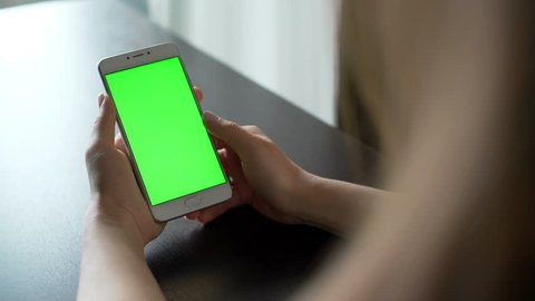 One person use cellular telephone with touch green screen for browsing social networks and communicating closeup. Girl, holding in hand portable gadget close up, as image of tech accessibility concept