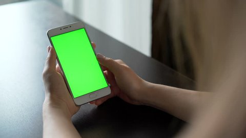 One person use cellular telephone with touch green screen for browsing social networks and communicating closeup. Girl, holding in hand portable gadget close up, as image of tech accessibility concept