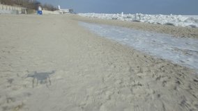 Drone flies sideways low over beach before climbing to reveal a frozen Black Sea. In Odessa Ukraine