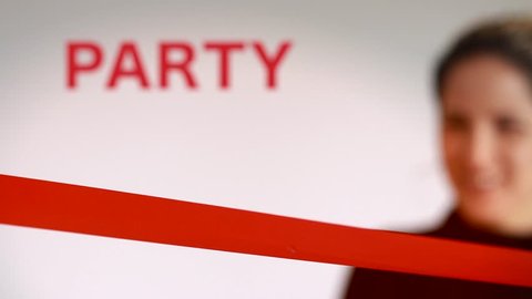 Woman cutting red ribbon at a party