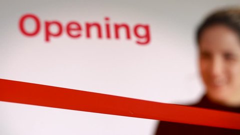 Woman cutting red ribbon at an opening event
