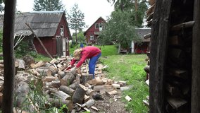 cottager split hard big log in country woodshed in summertime. 4K UHD video clip.  