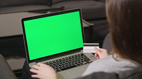 Close-up view of young woman online shoping at home on pc, typing credit card number