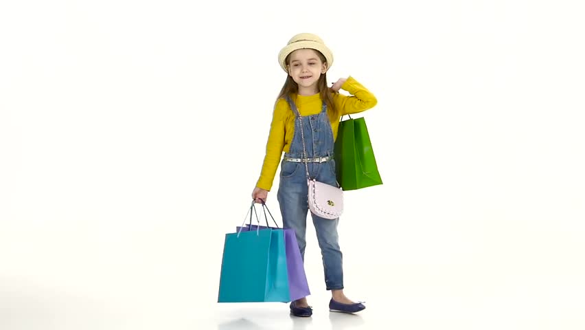 Little girl spinning with bags in their hands and behave affectedly. White background. Slow motion