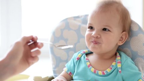 Mother gives baby food from a spoon