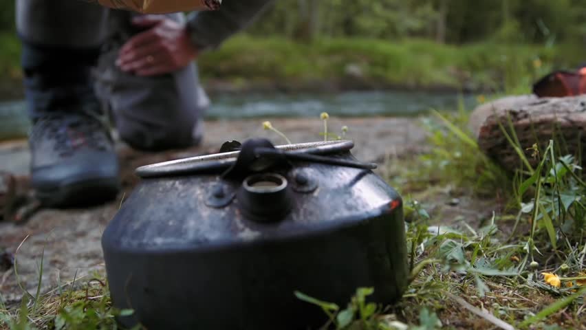 Pouring coffee beans in the coffee pot by the river