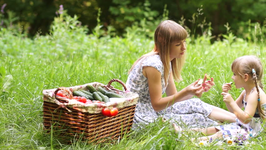 Mother and daughter with vegetables outdoors
