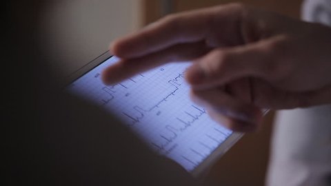 Doctor with colleagues examines the tablet cardiogram.
