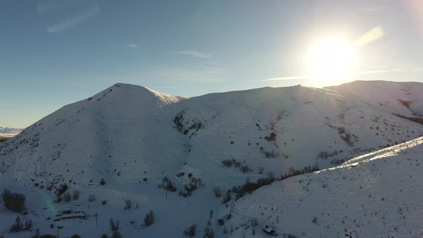 Long aerial pan shot of Hailey, Idaho in Sun Valley, Idaho covered in snow in winter with crystal clear blue sky, bright sunshine and beautiful white snow covered mountains.