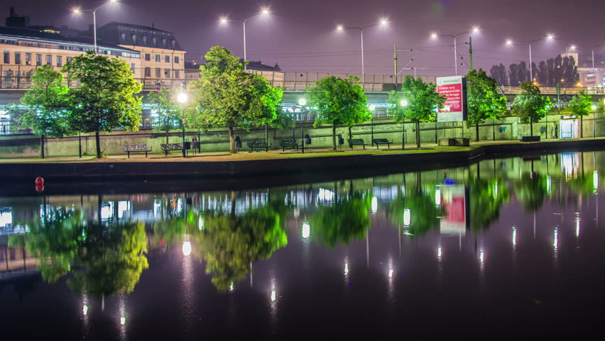Time Lapse Tilt of city park in Stockholm at night. Reflections in the calm water