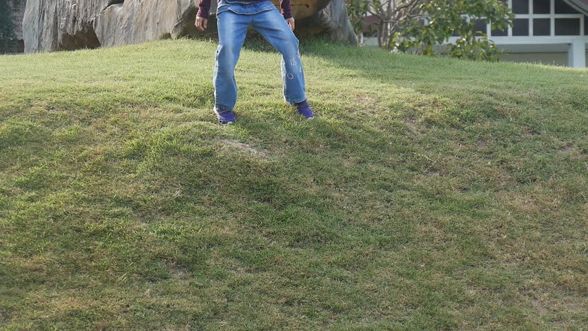 Asian girl running and sliding down on the grass at the park