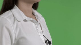 Placing wireless lavalier clip-on microphone on woman before an interview in chroma key studio