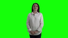 Woman with wireless lavalier clip-on microphone attached to her shirt talking to camera against a green screen