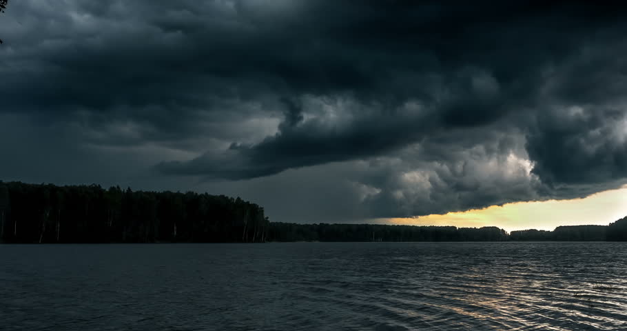 Dark stormy clouds float across the sky. Storm mooving over the river. Time lapse of storm clouds moving fast
