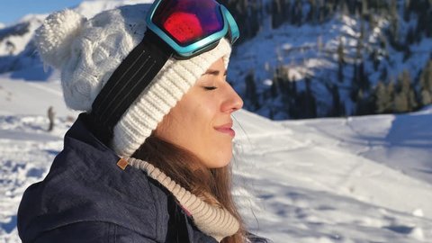 Portrait of beautiful young snowboarder woman looking at aerial view. Adventure to snowy mountains,. Snowboard and ski healthy activities. Happy and funny girl