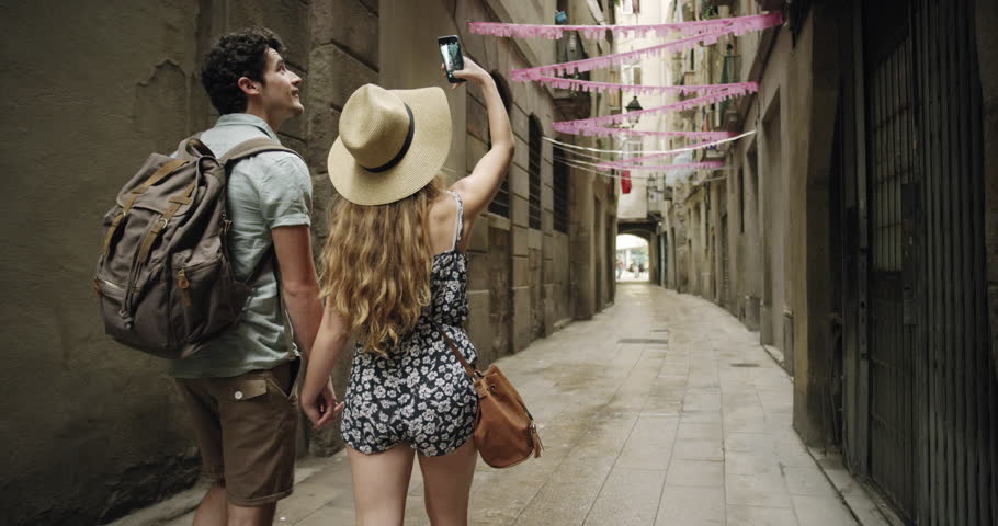 Tourist couple taking photograph with smartphone streets of Barcelona Sightseeing enjoying European summer holiday travel vacation adventure
