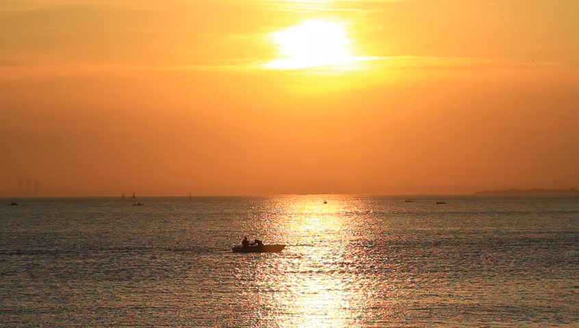 Calm sea with a rowing boat at sunset