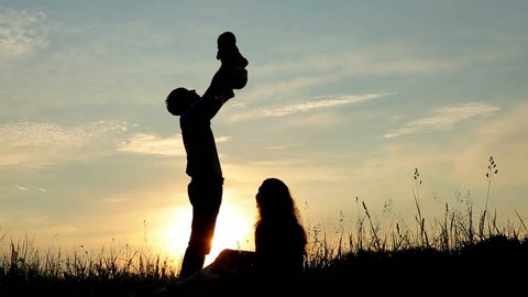 Happy family: father, mother and baby playing at sunset. Silhouettes