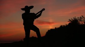 Spanish musician playing guitar on sunset background. Silhouette video