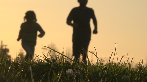 Blurry silhouette of kids running at sunset