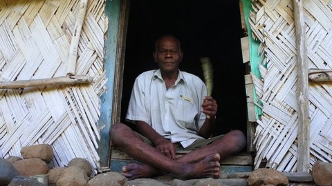 Elderly indigenous Fijian man in his 70's sit outside his village bure home in Navala village in Ba highlands on Viti Levu island, Fiji. Real people. Copy space