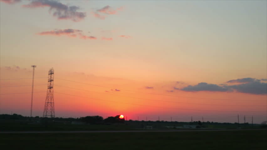 A lazy Texas sunset follows travelers along a country highway and up and overpass.