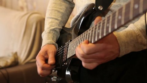 man plays the electric guitar standing in the room.