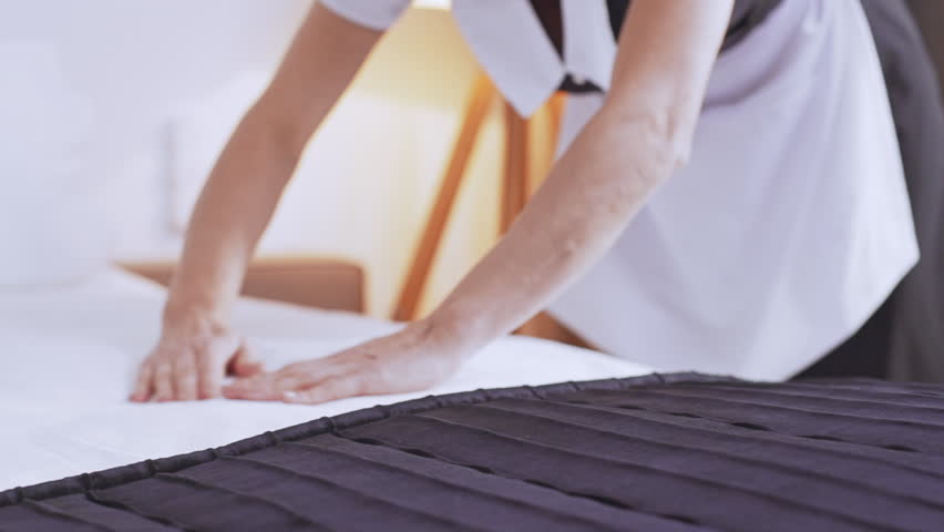 Middle-aged Caucasian chambermaid in uniform making bed in the morning in slowmotion Royalty-Free Stock Footage #24083479