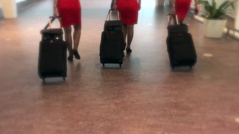 stewardess crew in red dresses walks along passage