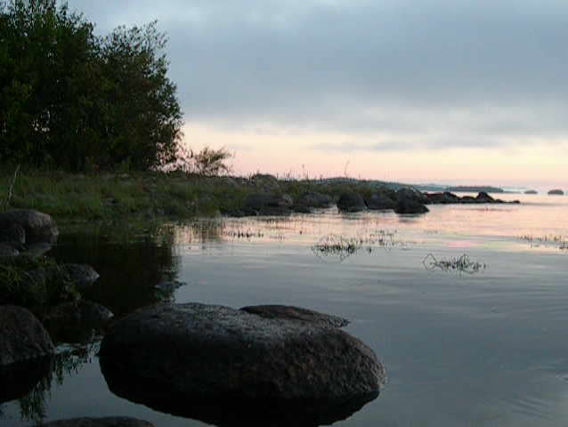 Slow pink sunrise on a lake with view on rock island